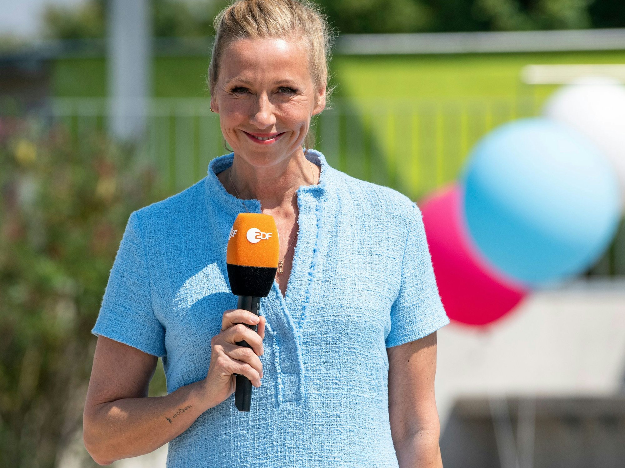 "ZDF-Fernsehgarten: Moderatorin Andrea Kiewel steht im "Fernsehgarten" und lächelt in die Kamera.