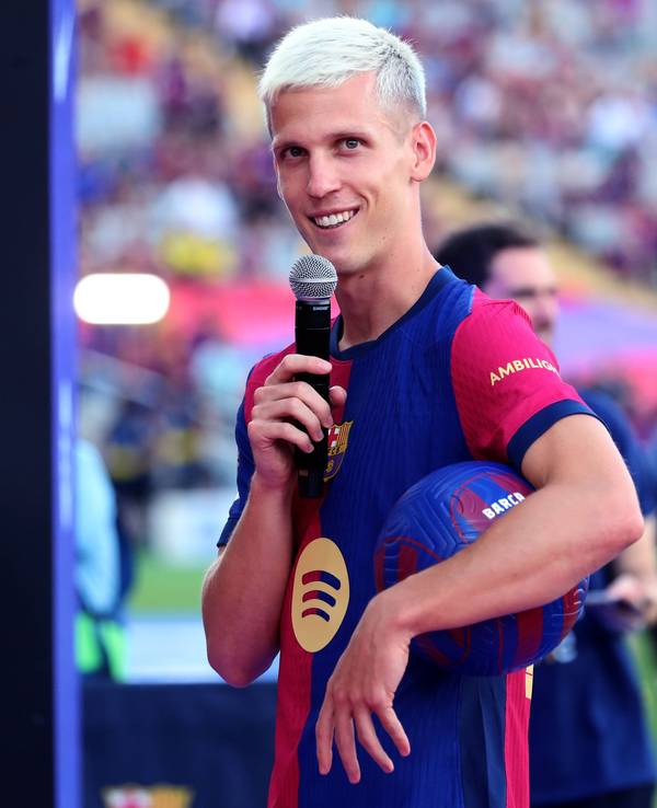 Dani Olmo bei der Kaderpräsentation des FC Barcelona mit einem Mikrophon in der Hand und einem Ball unter dem Arm.