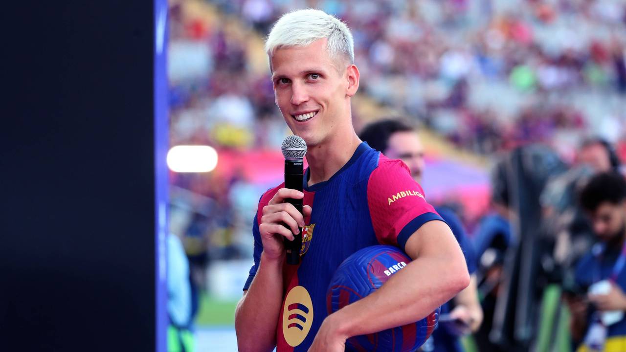 Dani Olmo bei der Kaderpräsentation des FC Barcelona mit einem Mikrophon in der Hand und einem Ball unter dem Arm.