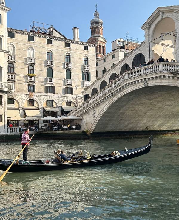 Eine Gondel mit Touristen vor der Rialto-Brücke im Zentrum von Venedig.