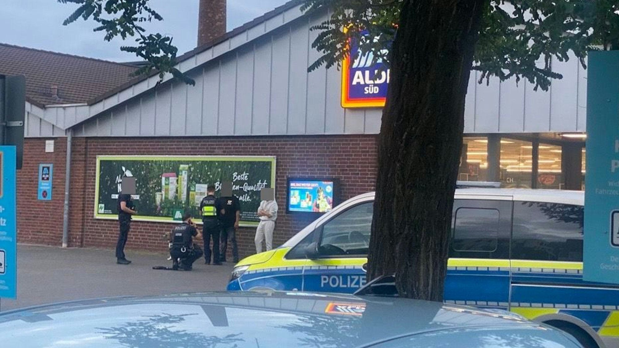 Polizisten stehen bei einem Einsatz neben zwei Männern.