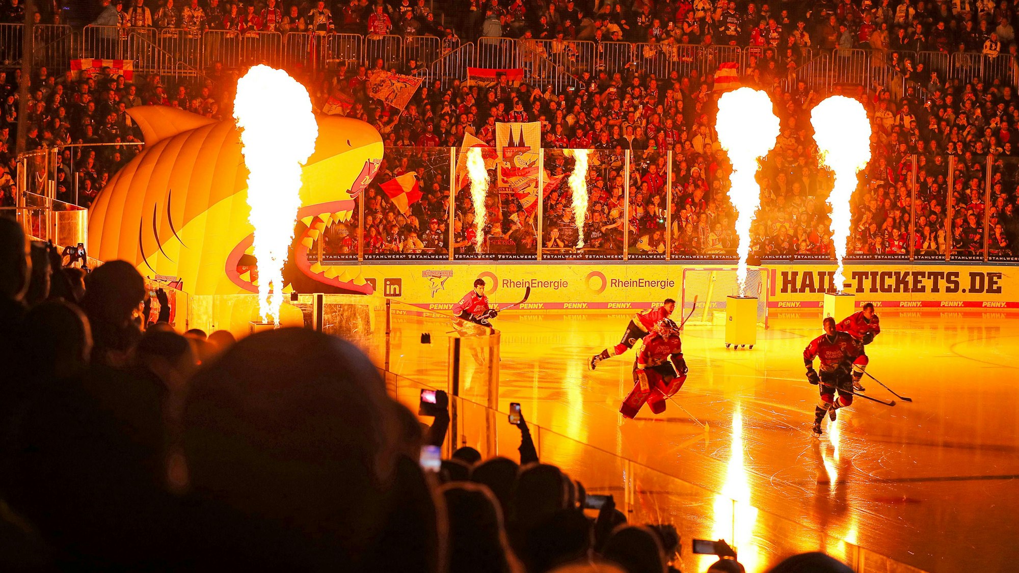 Die Spieler der Kölner Haie stürmen in der Lanxess-Arena vor einem DEL-Spiel aufs Eis.