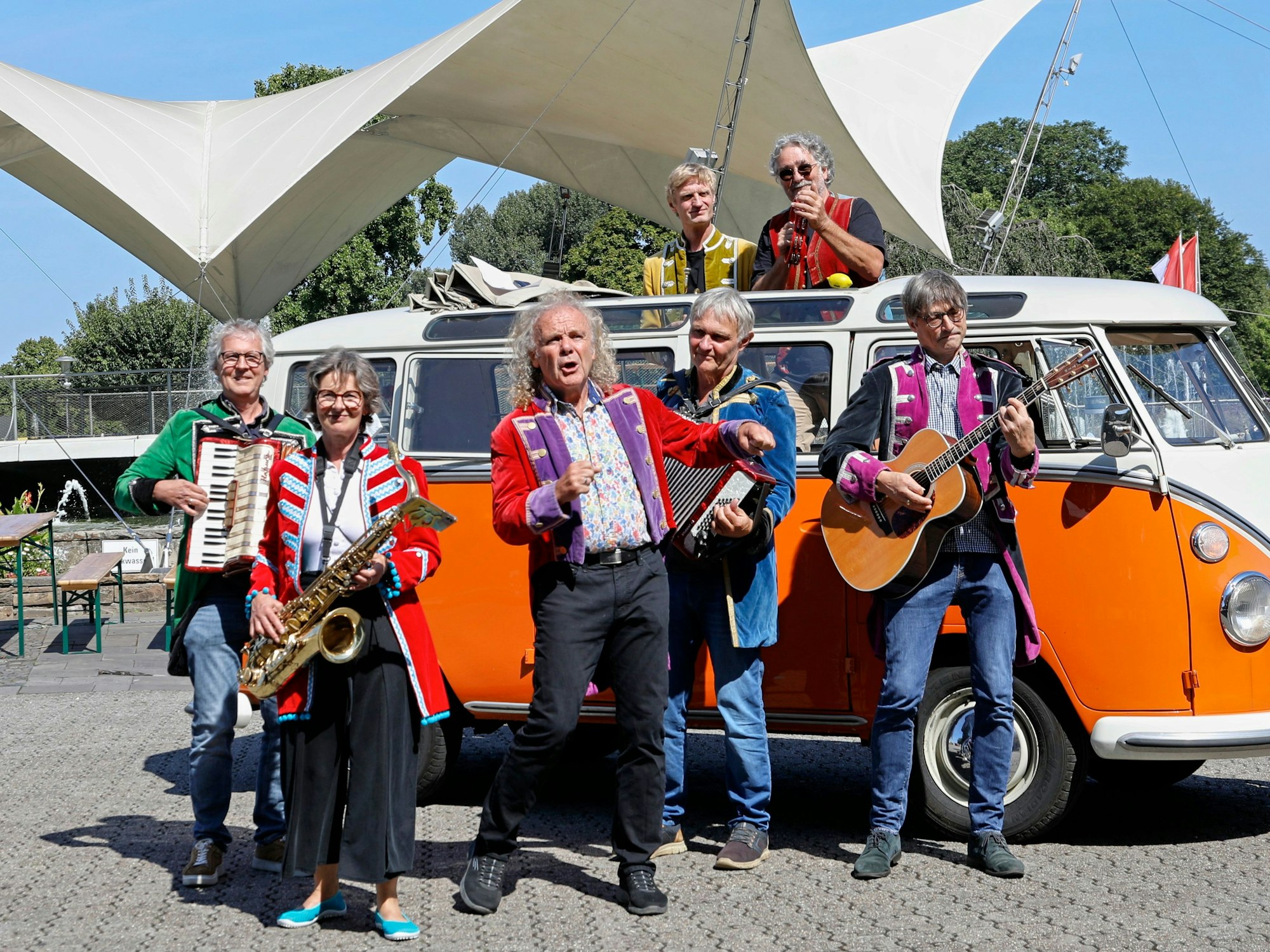 Eine Band steht vor einem VW Bus.
