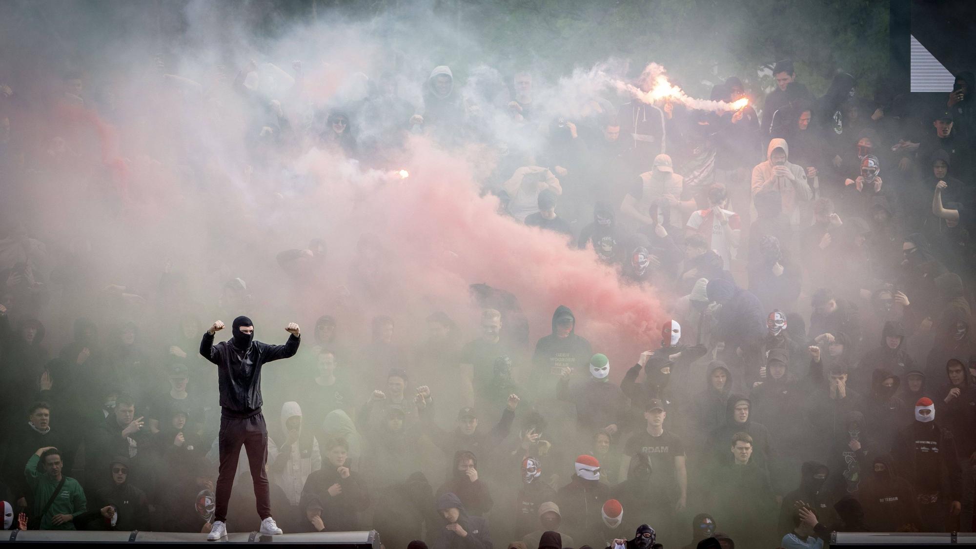Vermummte Anhänger von Feyenoord zünden Rauchbomben.