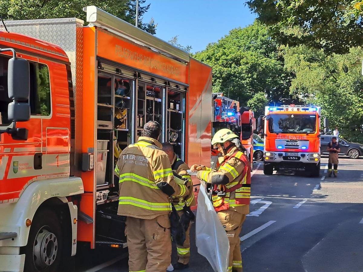 Drei Feuerwehrleute stehen an einem Löschfahrzeug, dahinter stehen weitere Löschfahrzeuge.