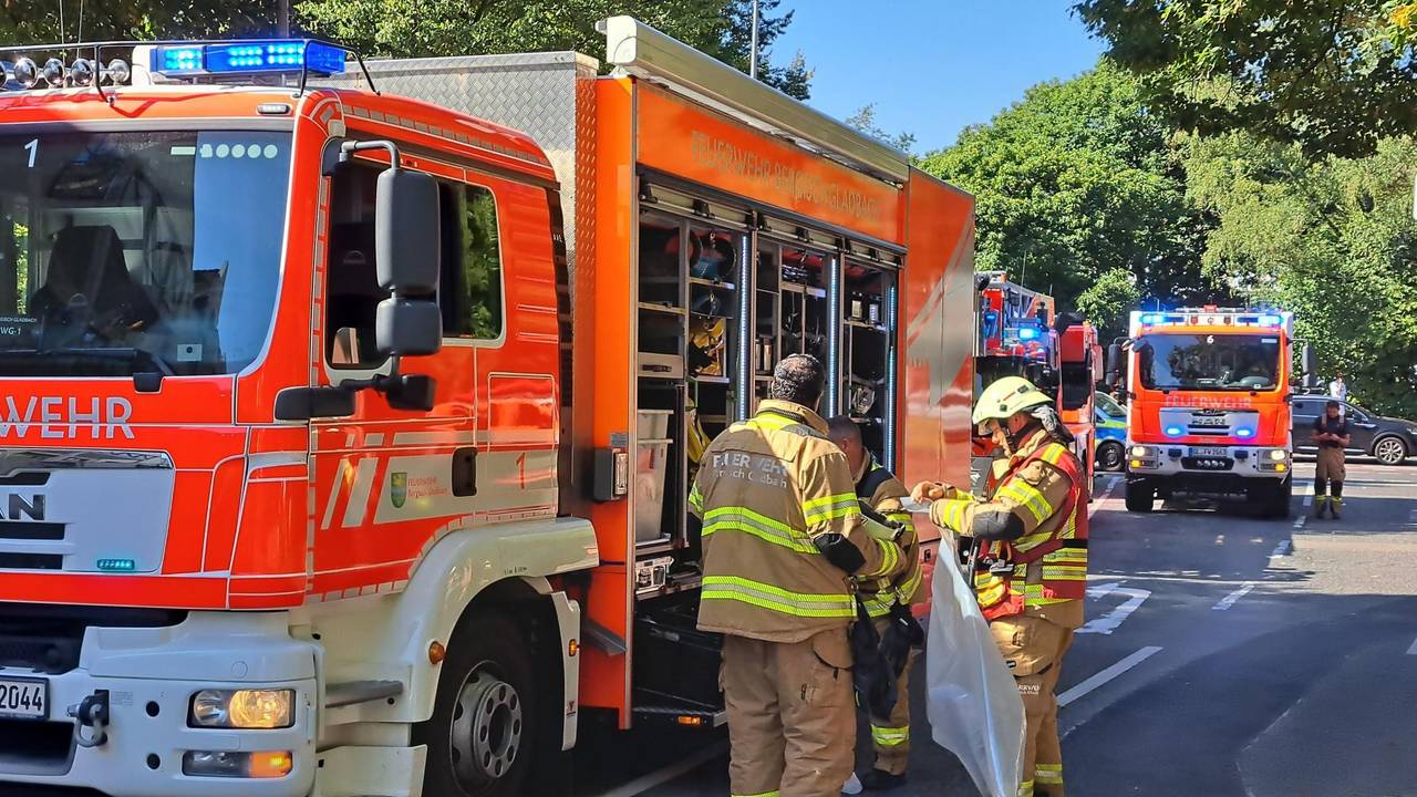 Drei Feuerwehrleute stehen an einem Löschfahrzeug, dahinter stehen weitere Löschfahrzeuge.