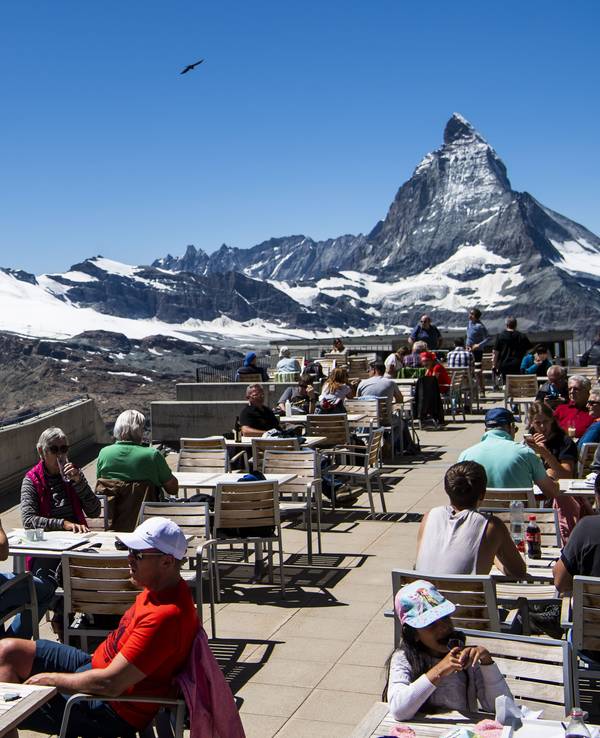 Touristen und Touristinnen sitzen auf der Terrasse vom Gornergrat vor dem Matterhorn.