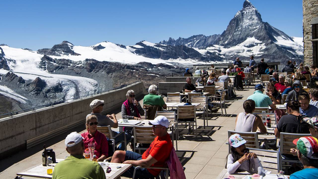 Touristen und Touristinnen sitzen auf der Terrasse vom Gornergrat vor dem Matterhorn.