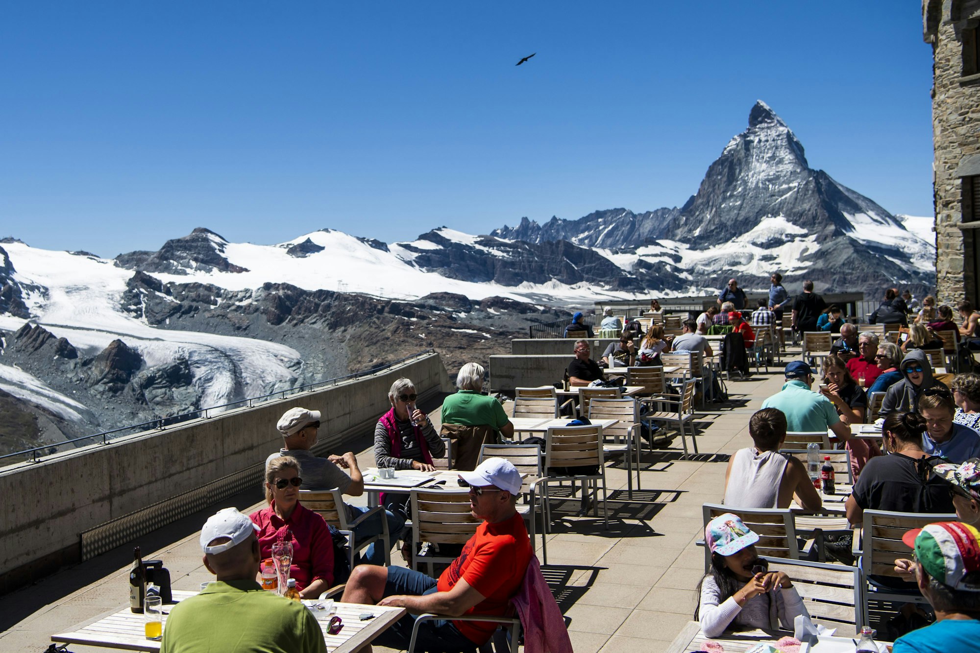 Touristen und Touristinnen sitzen auf der Terrasse vom Gornergrat vor dem Matterhorn.
