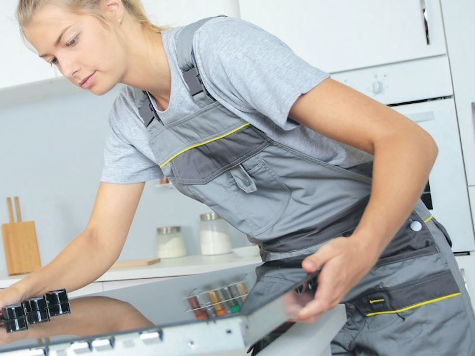 Handwerkerin beim Einbau eines Herdes.