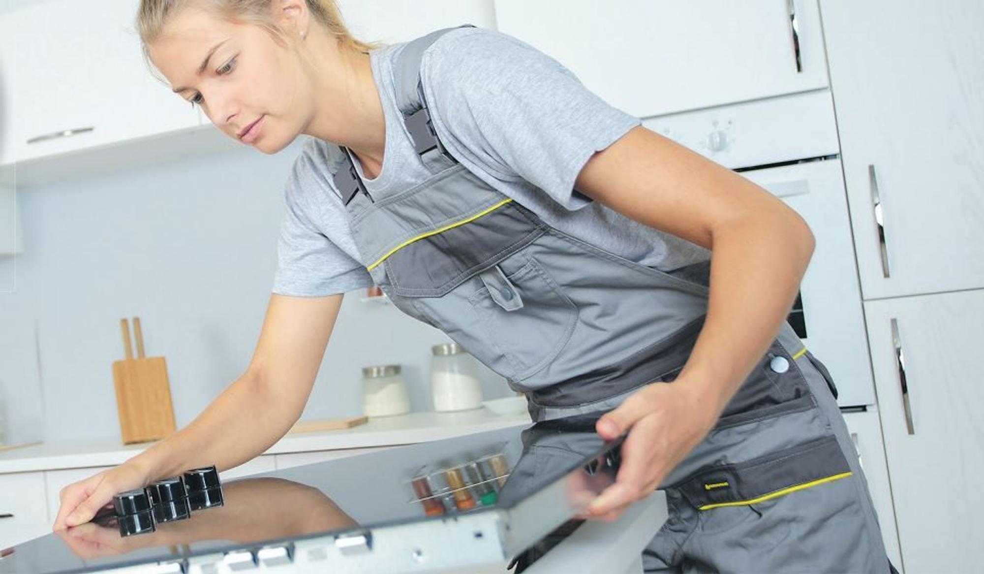 Handwerkerin beim Einbau eines Herdes.