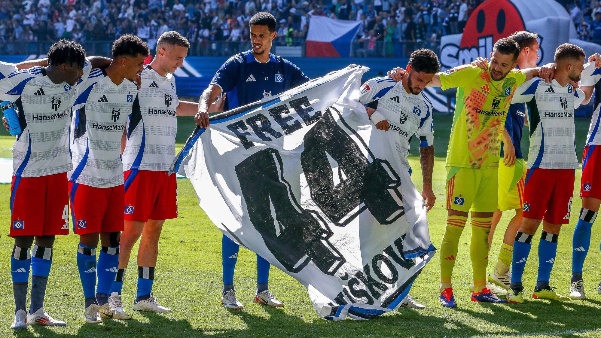 Silvan Hefti, Robert Glatzel und Ludovit Reis halten ein Banner mit der Aufschrift „Free Vuskovic“.