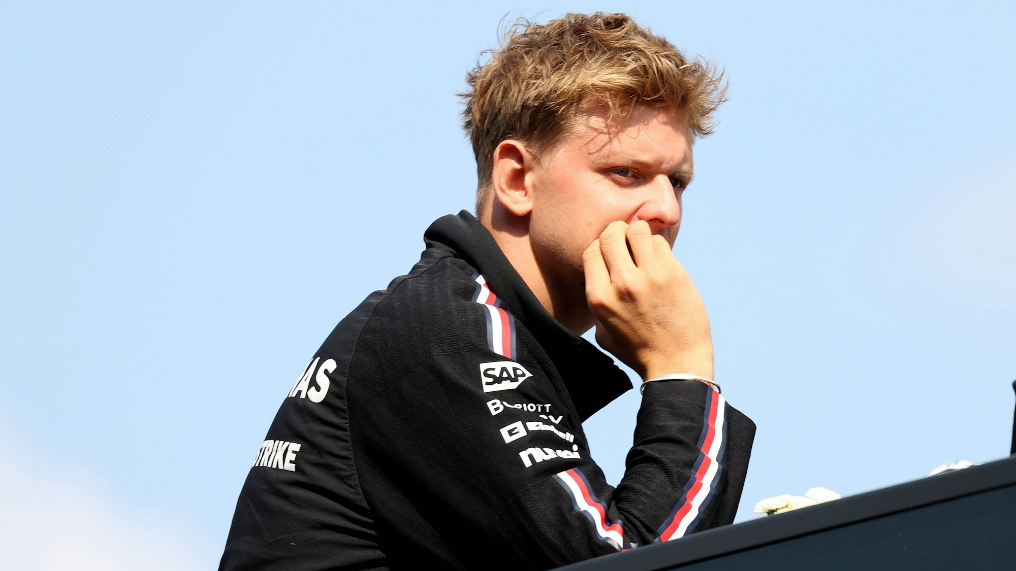 Mick Schumacher fasst sich ins Gesicht und blickt grimmig.