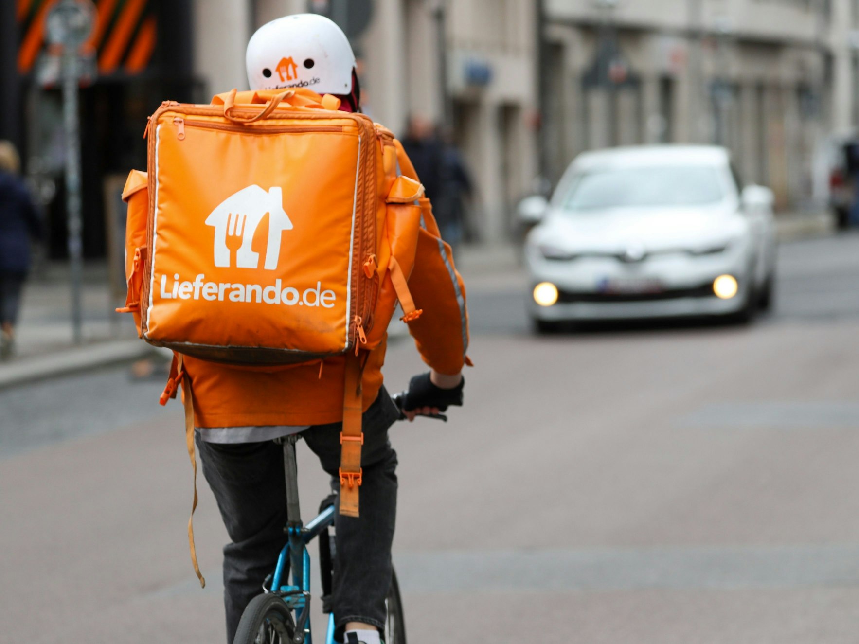 Ein Fahrradbote vom Lieferdienst Lieferando.de fährt über eine Straße.