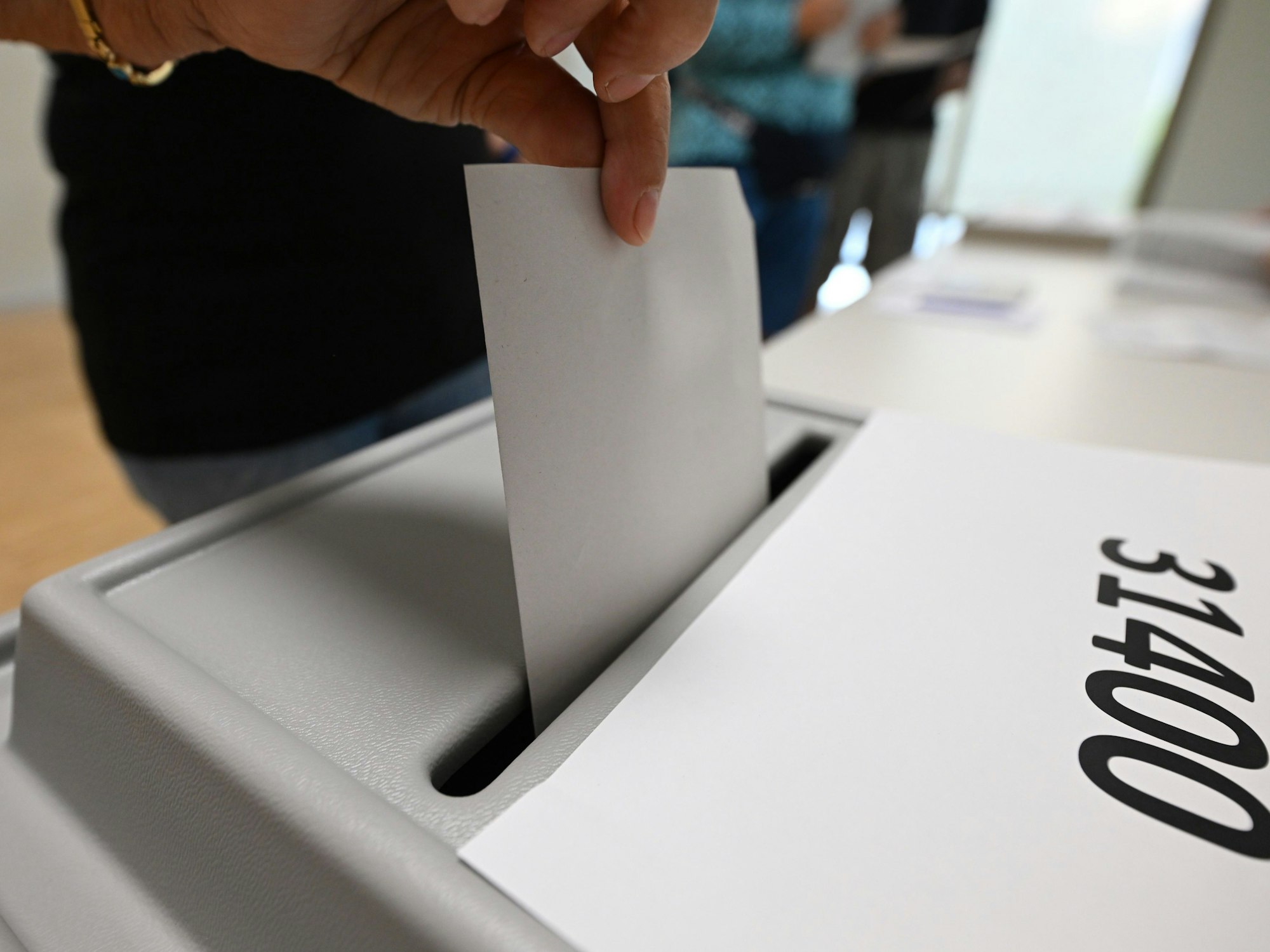 Eine Frau wirft bei der Stimmabgabe zur Landtagswahl in Sachsen in einem Wahllokal ihren Stimmzettel in die Wahlurne.