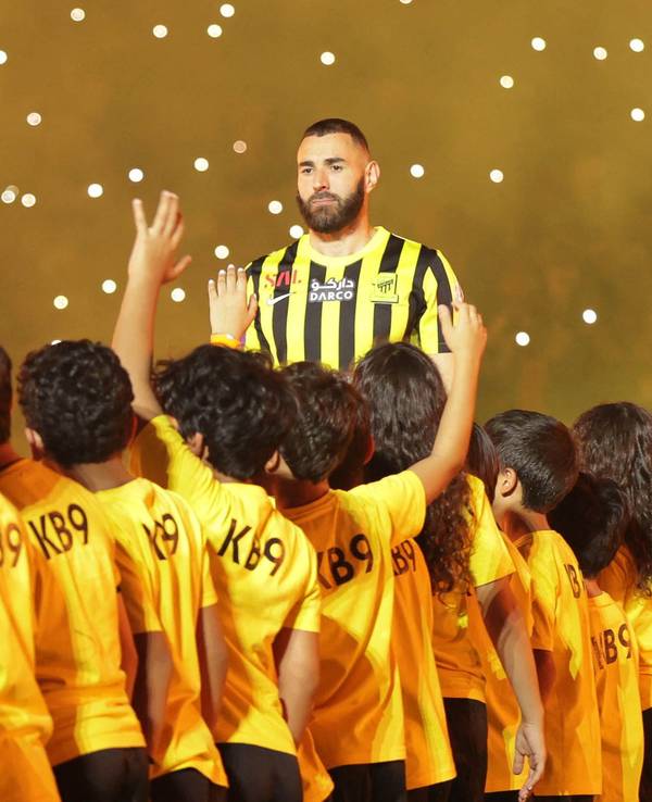 Karim Benzema ist bei der Vereinsvorstellung als neuer Al-Ittihad Spieler von Kindern umgeben.