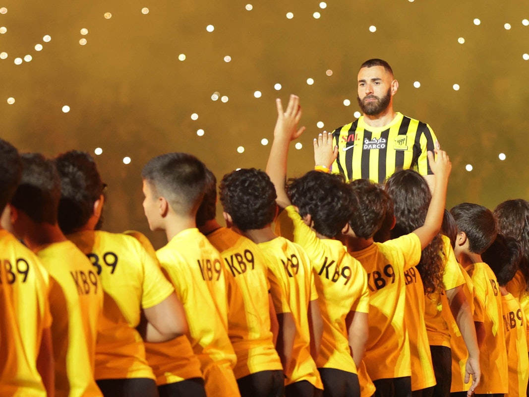 Karim Benzema ist bei der Vereinsvorstellung als neuer Al-Ittihad Spieler von Kindern umgeben.
