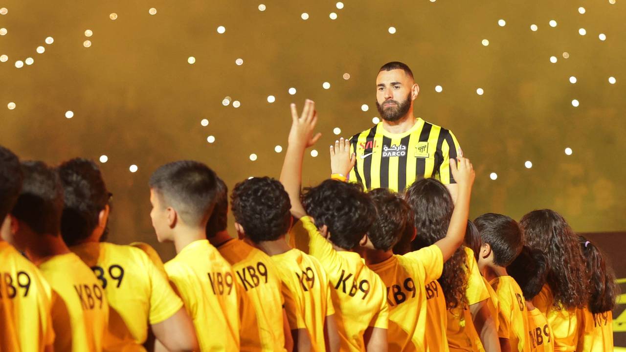 Karim Benzema ist bei der Vereinsvorstellung als neuer Al-Ittihad Spieler von Kindern umgeben.