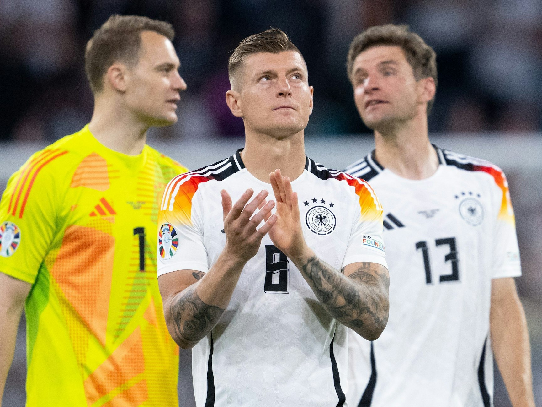 Torhüter Manuel Neuer (l-r), Toni Kroos und Thomas Müller von Deutschland stehen nach dem Spiel auf dem Platz.