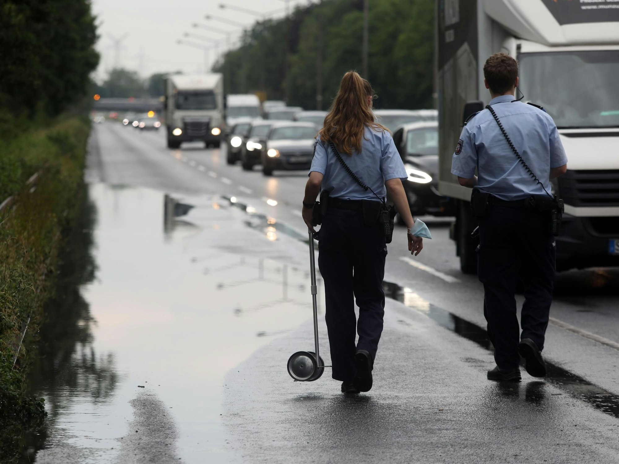 Beamte laufen nach einem Unfall über die Industriestraße in Köln.