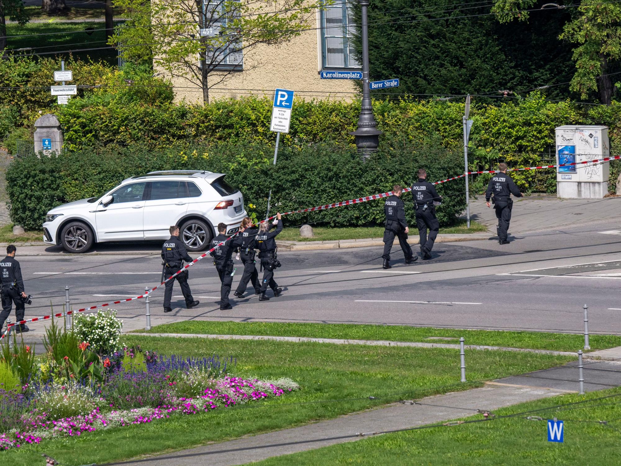 Polizisten gehen eine Straße am Karolinenplatz auf der Suche nach Spuren ab.