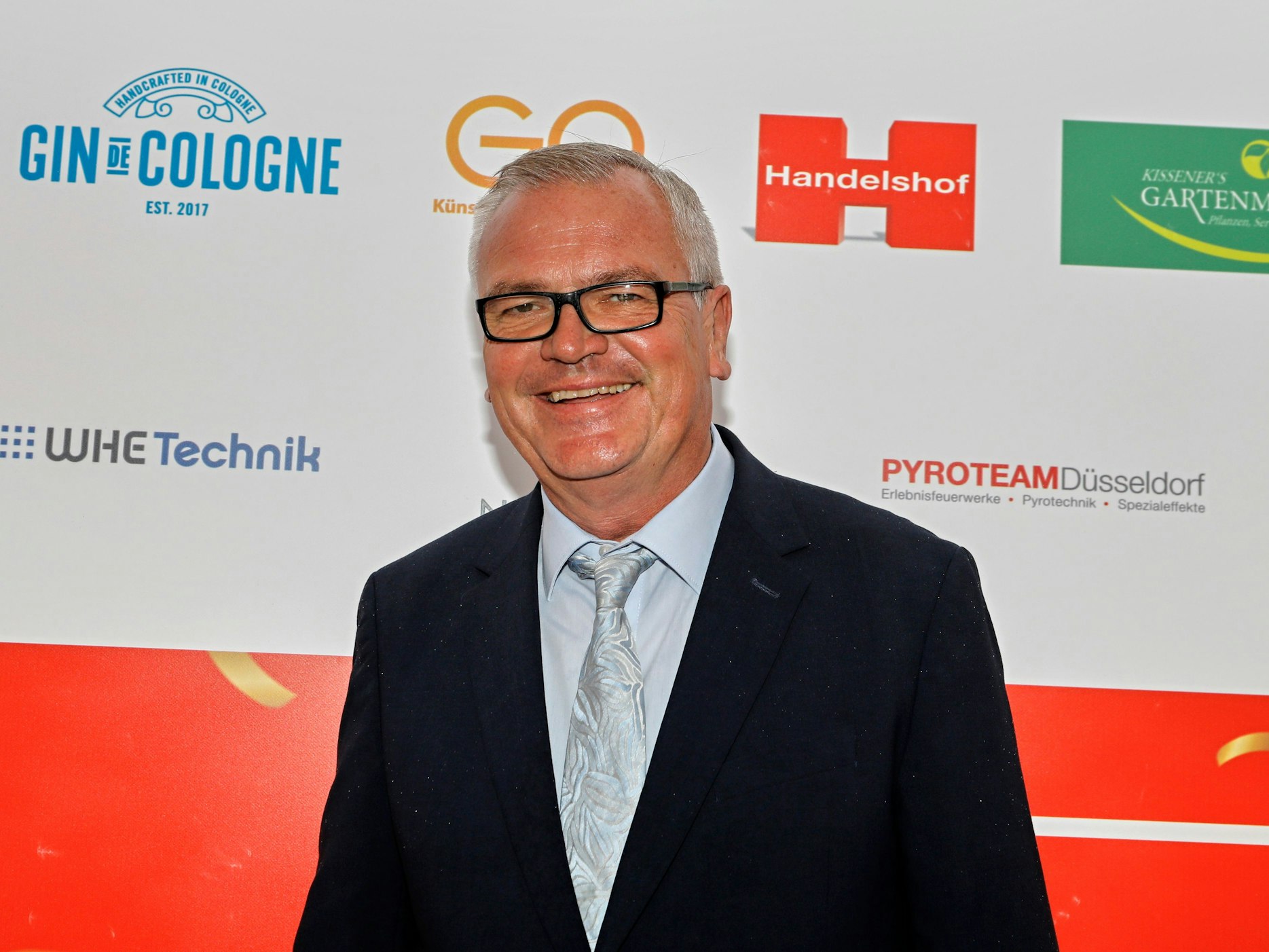 Jürgen Beckers steht auf dem roten Teppich.