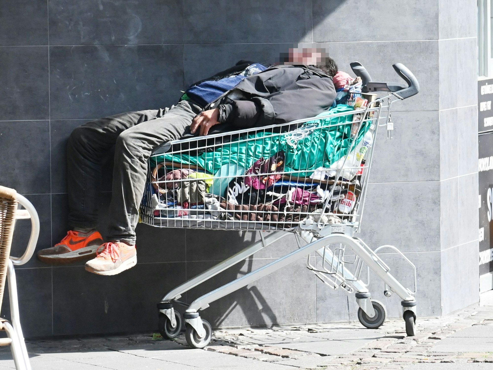 Ein Obdachloser schläft in einem Einkaufswagen auf der Merowingerstraße in Köln.