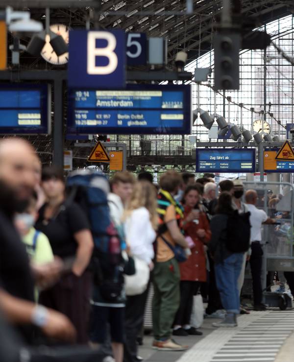 Menschen stehen an Gleis 5 des Kölner Hauptbahnhofs und warten auf einen Zug.