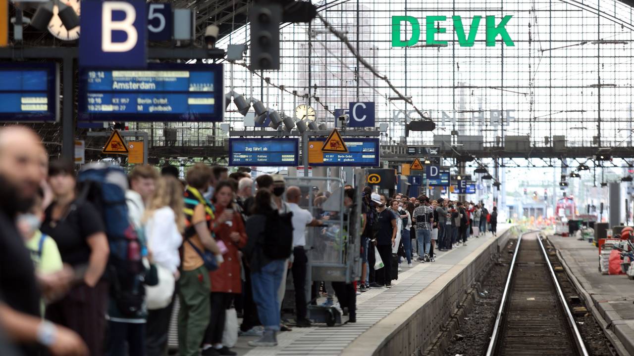 Menschen stehen an Gleis 5 des Kölner Hauptbahnhofs und warten auf einen Zug.