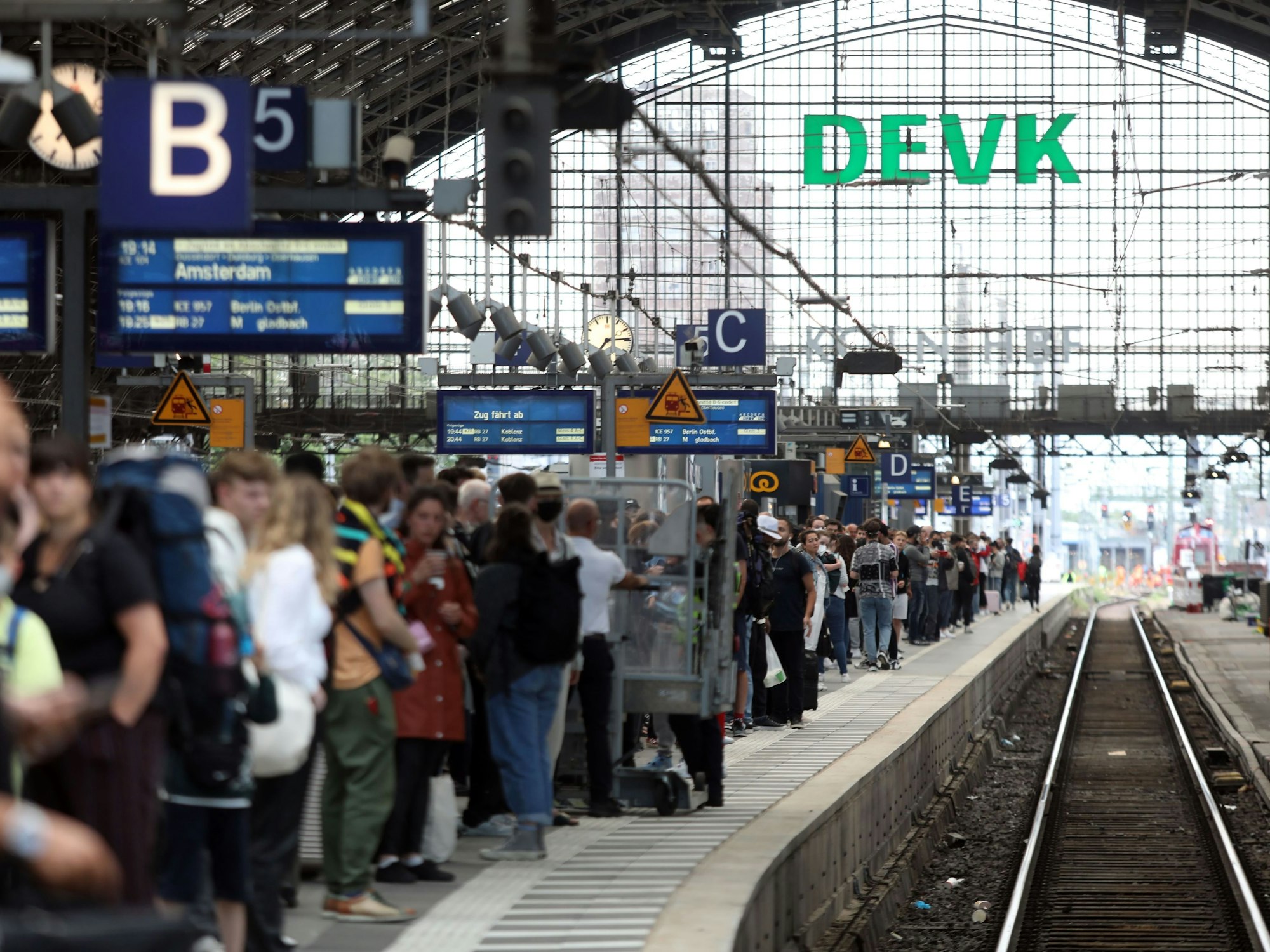Menschen stehen an Gleis 5 des Kölner Hauptbahnhofs und warten auf einen Zug.