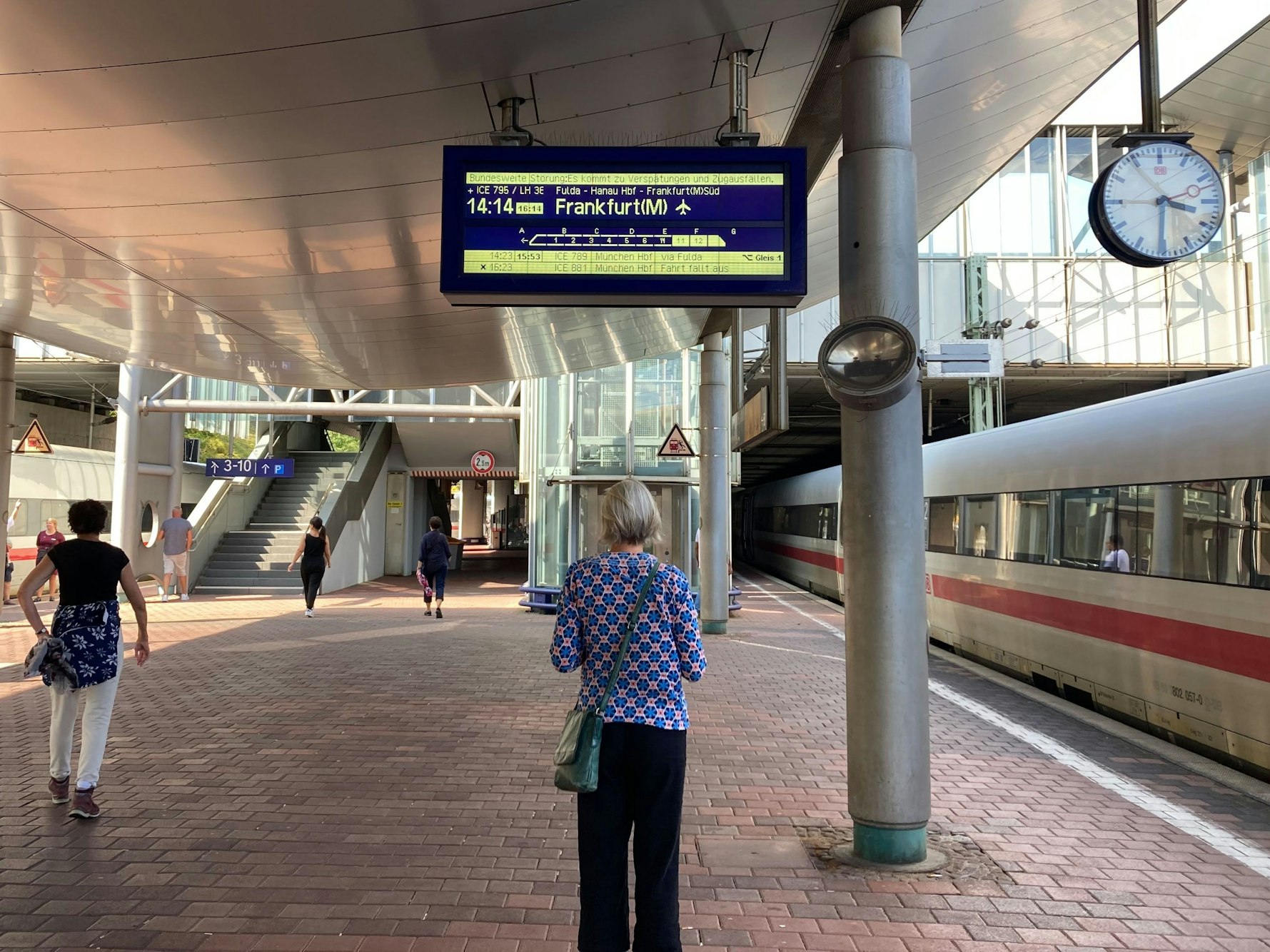 Ein Frau steht am Samstag, 7. September 2024, auf dem Bahnsteig in Kassel und schaut sich eine Anzeige der Deutsche Bahn an.