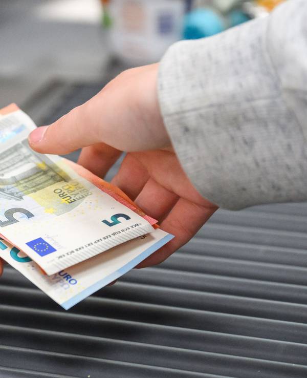 Eine Kassiererin gibt einer Kundin Geld an der Kasse eines Supermarktes.