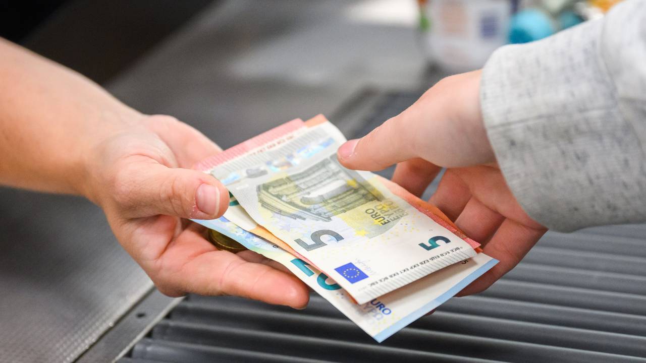 Eine Kassiererin gibt einer Kundin Geld an der Kasse eines Supermarktes.