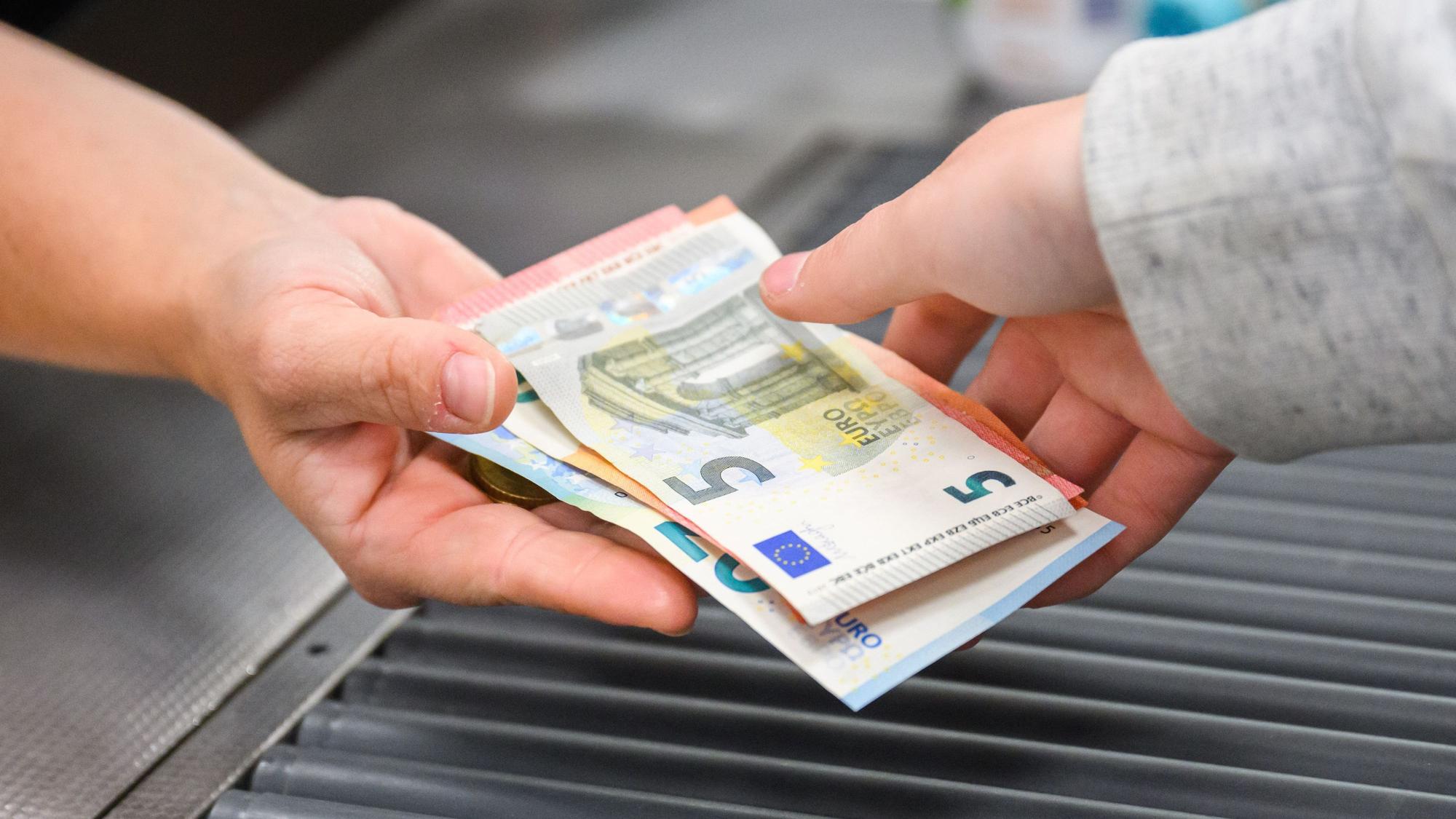 Eine Kassiererin gibt einer Kundin Geld an der Kasse eines Supermarktes.