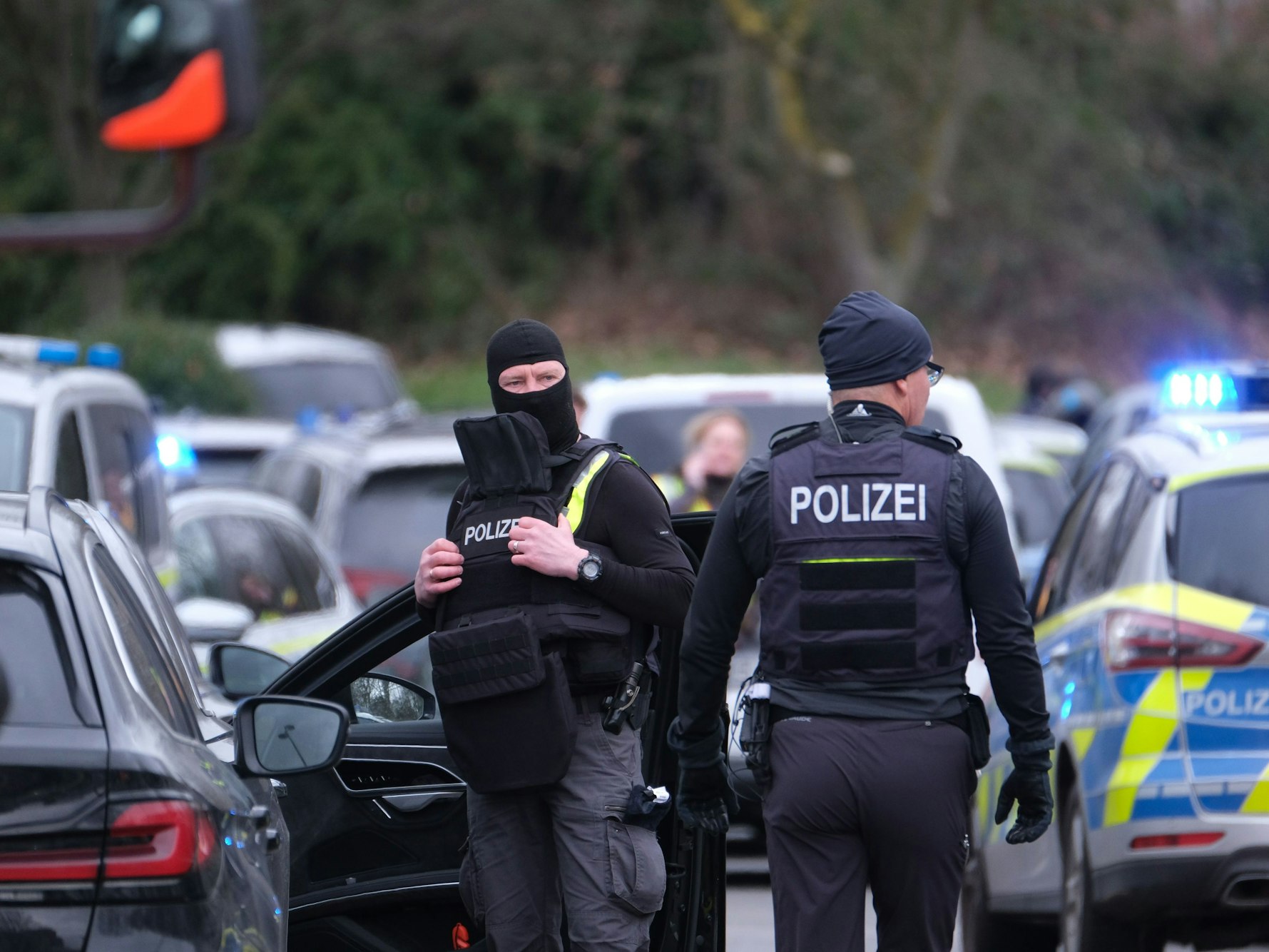 Beamte stehen bei einem Einsatz vor den Streifenfahrzeugen.