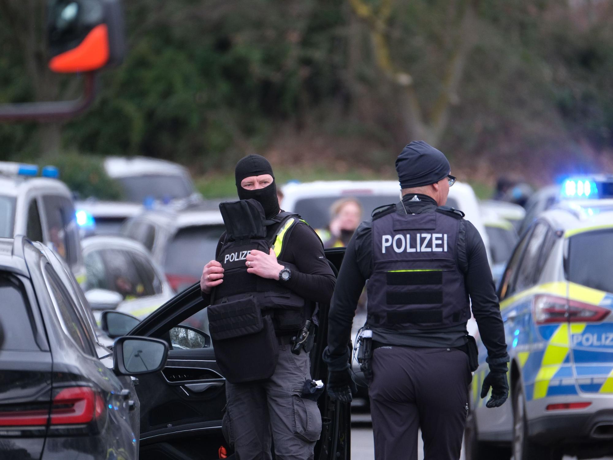 Beamte stehen bei einem Einsatz vor den Streifenfahrzeugen.