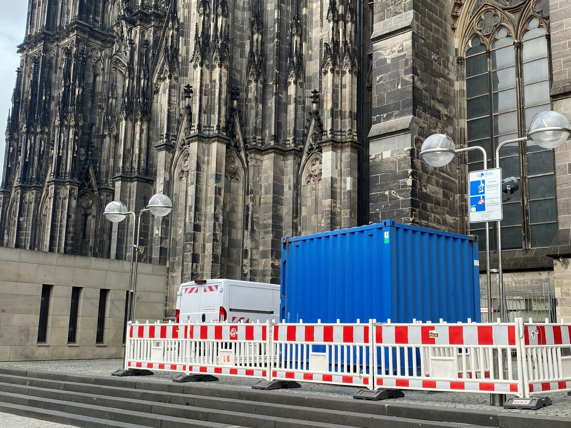 Absperrbaken und ein blauer Container vor dem Kölner Dom.