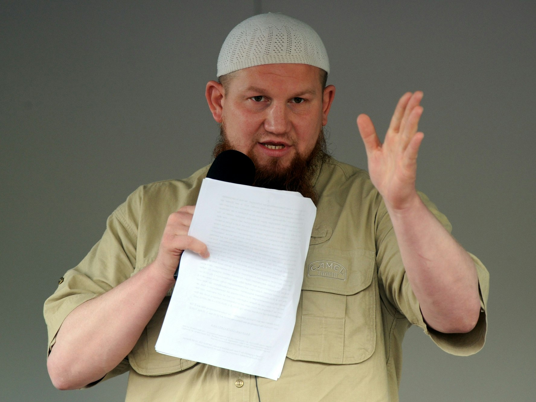 Ein Mann spricht auf einer Bühne in ein Mikrofon.