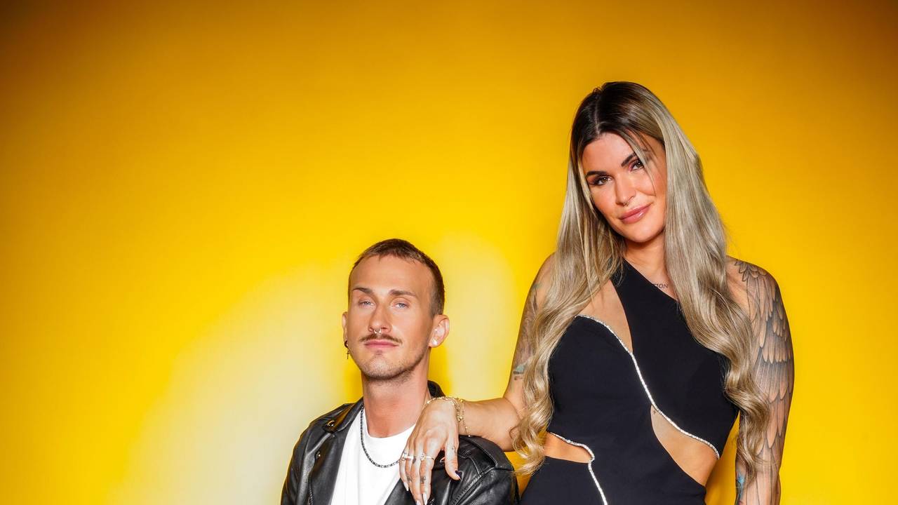 Das Foto zeigt Gloria Glumac und ihren Freund Michael vor einer gelben Wand. Sie steht, er sitzt auf einem Koffer.