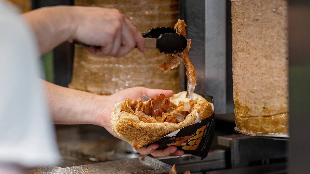 Ein Mitarbeiter einer Dönerbude legt Fleisch in einen Döner (Symbolbild): Das NRW-Ministerium nimmt den Döner ins Visier.