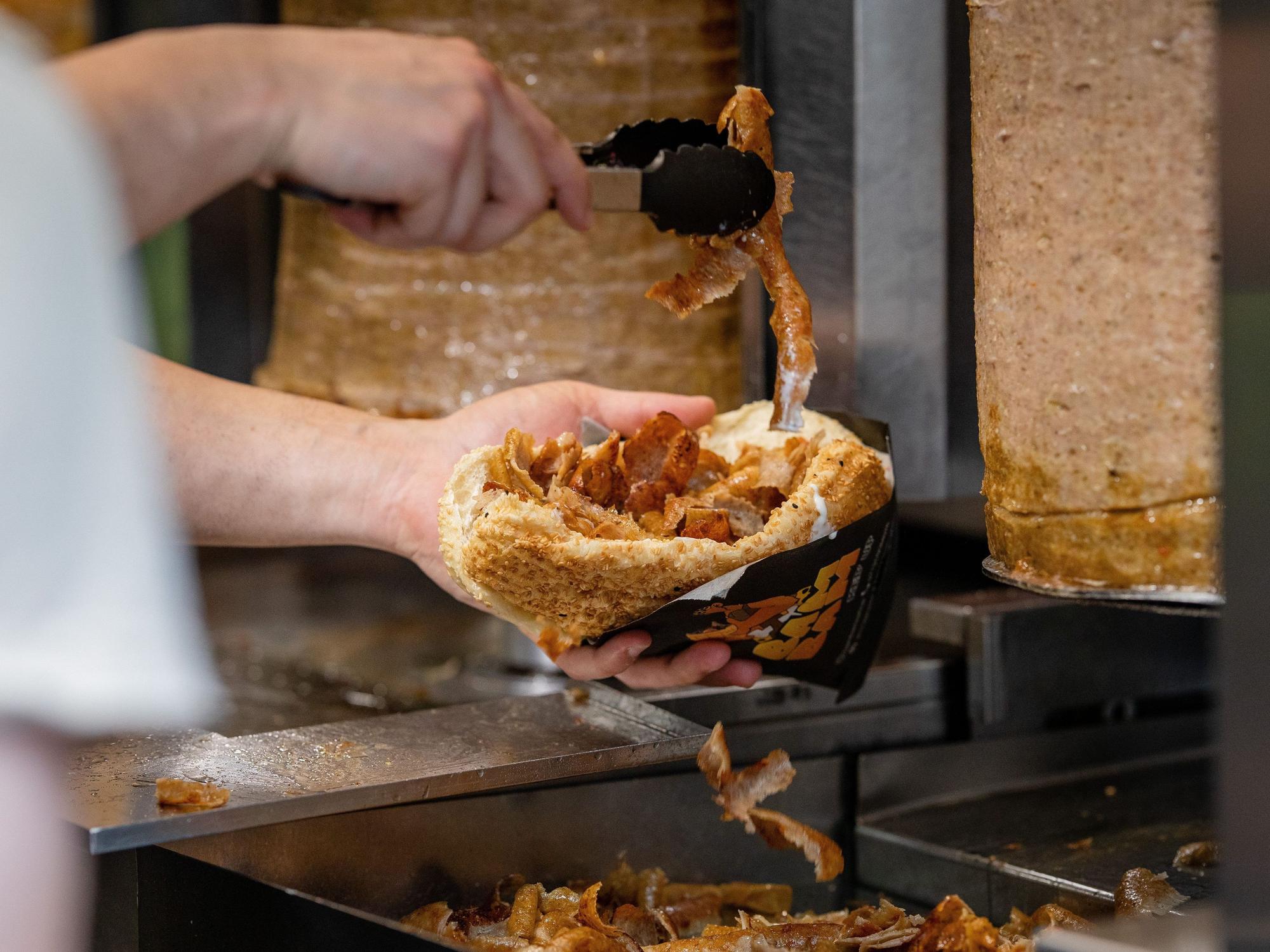 Ein Mitarbeiter einer Dönerbude legt Fleisch in einen Döner (Symbolbild): Das NRW-Ministerium nimmt den Döner ins Visier.