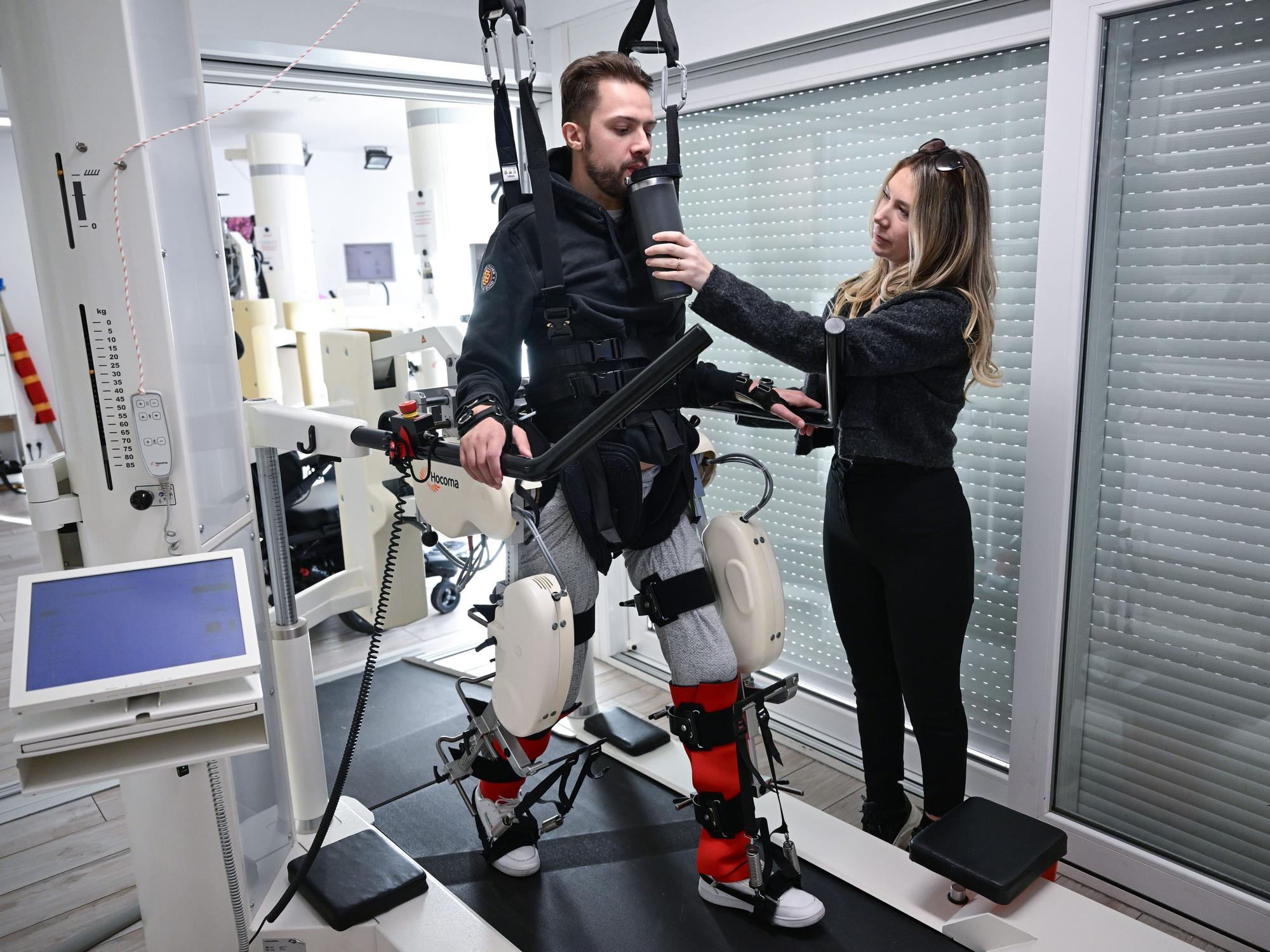 Der ehemalige Eishockeyspieler Mike Glemser () absolviert in einer Reha eine Übungseinheit bei einer Robotergestützten Gangtherapie. Rechts seine Freundin und Stütze Lara Lindmayer.