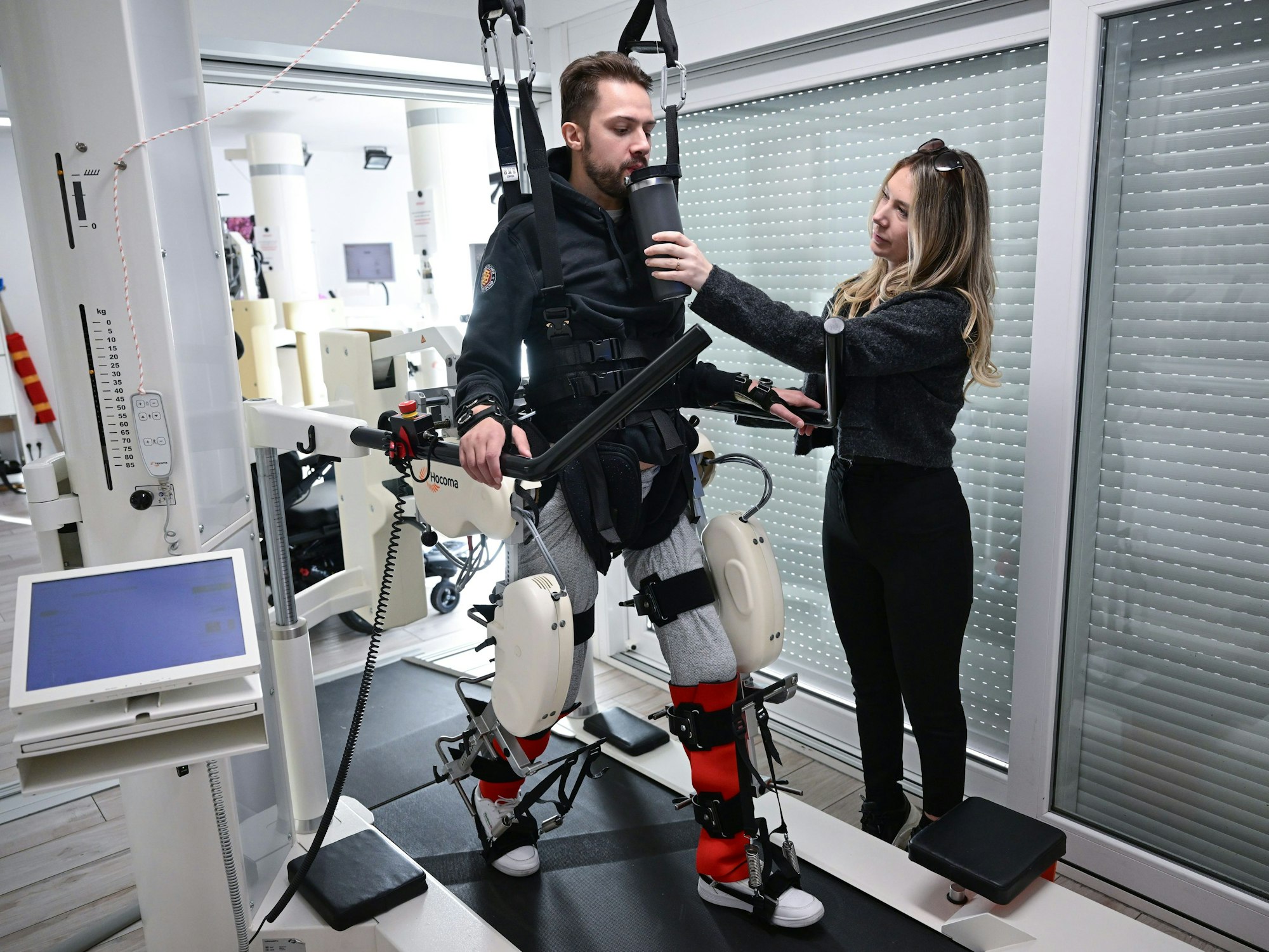 Der ehemalige Eishockeyspieler Mike Glemser () absolviert in einer Reha eine Übungseinheit bei einer Robotergestützten Gangtherapie. Rechts seine Freundin und Stütze Lara Lindmayer.