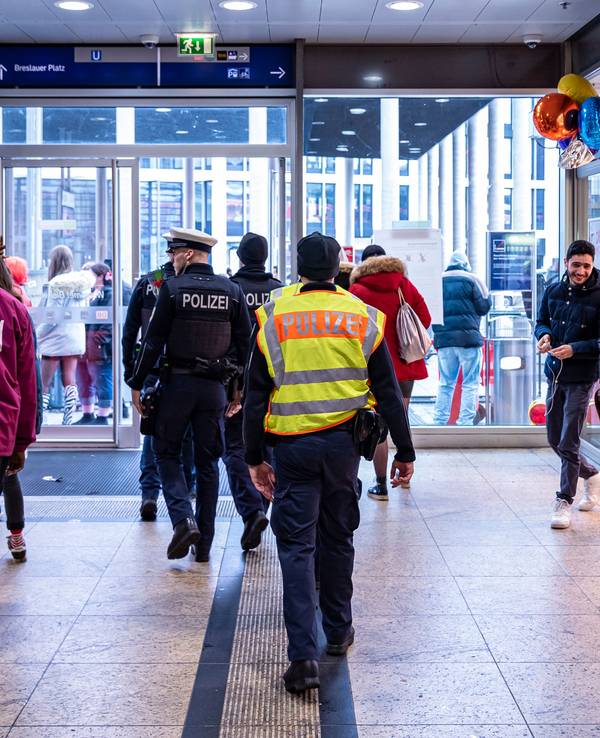 Menschen gehen an Rosenmontag durch den Kölner Hauptbahnhof, auch eine Streife der Polizei ist zu sehen.