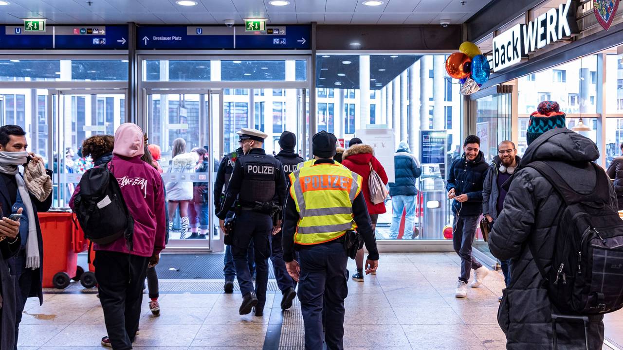 Menschen gehen an Rosenmontag durch den Kölner Hauptbahnhof, auch eine Streife der Polizei ist zu sehen.