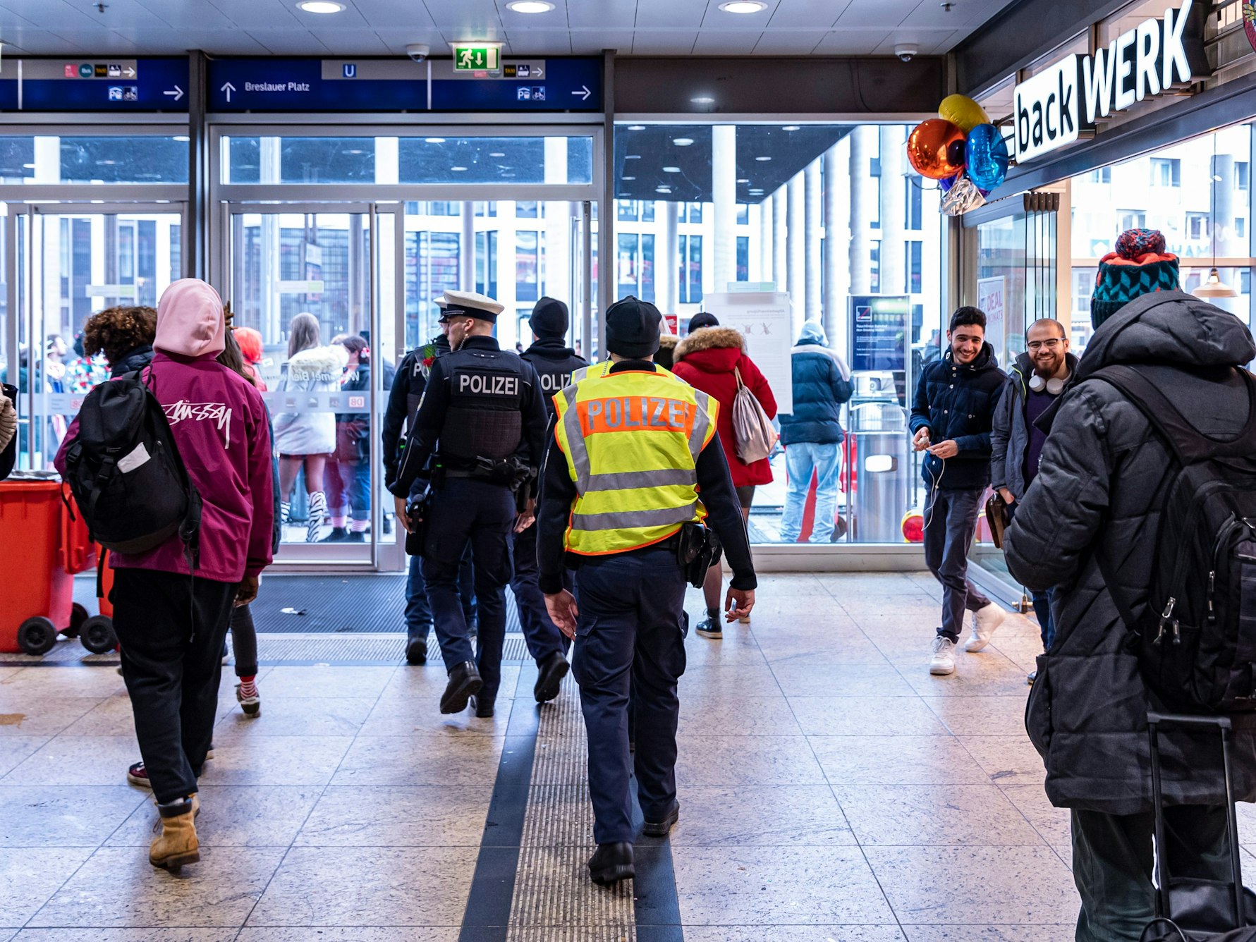 Menschen gehen an Rosenmontag durch den Kölner Hauptbahnhof, auch eine Streife der Polizei ist zu sehen.