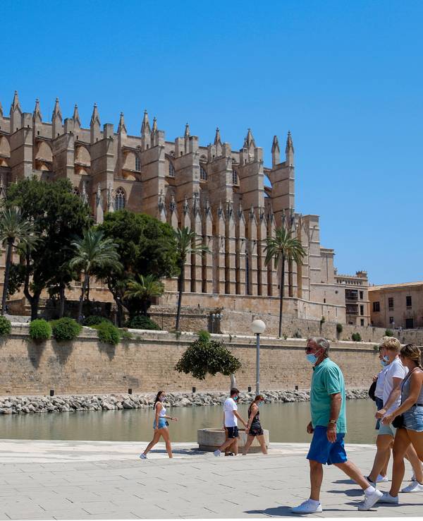 Touristen und Touristinnen gehen vor der Kathedrale in Palma de Mallorca entlang.