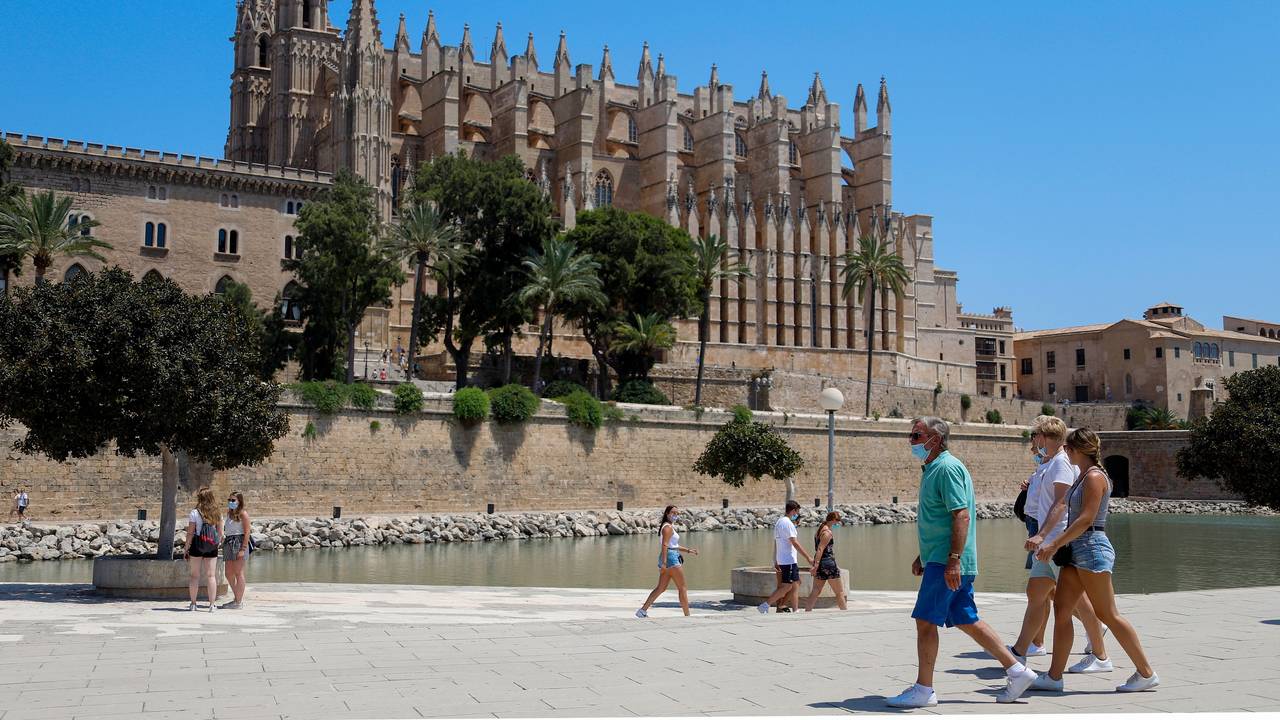 Touristen und Touristinnen gehen vor der Kathedrale in Palma de Mallorca entlang.