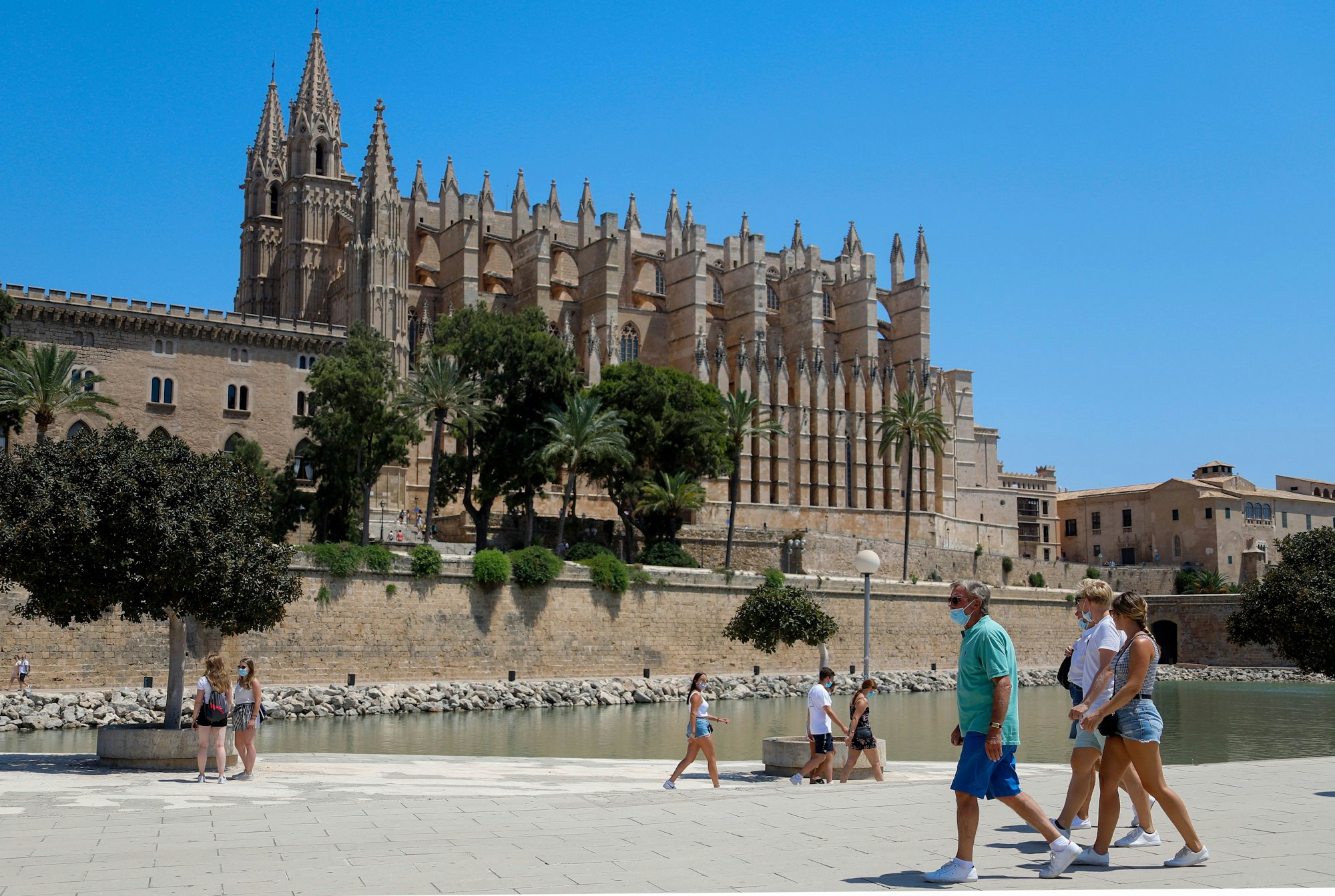 Touristen und Touristinnen gehen vor der Kathedrale in Palma de Mallorca entlang.