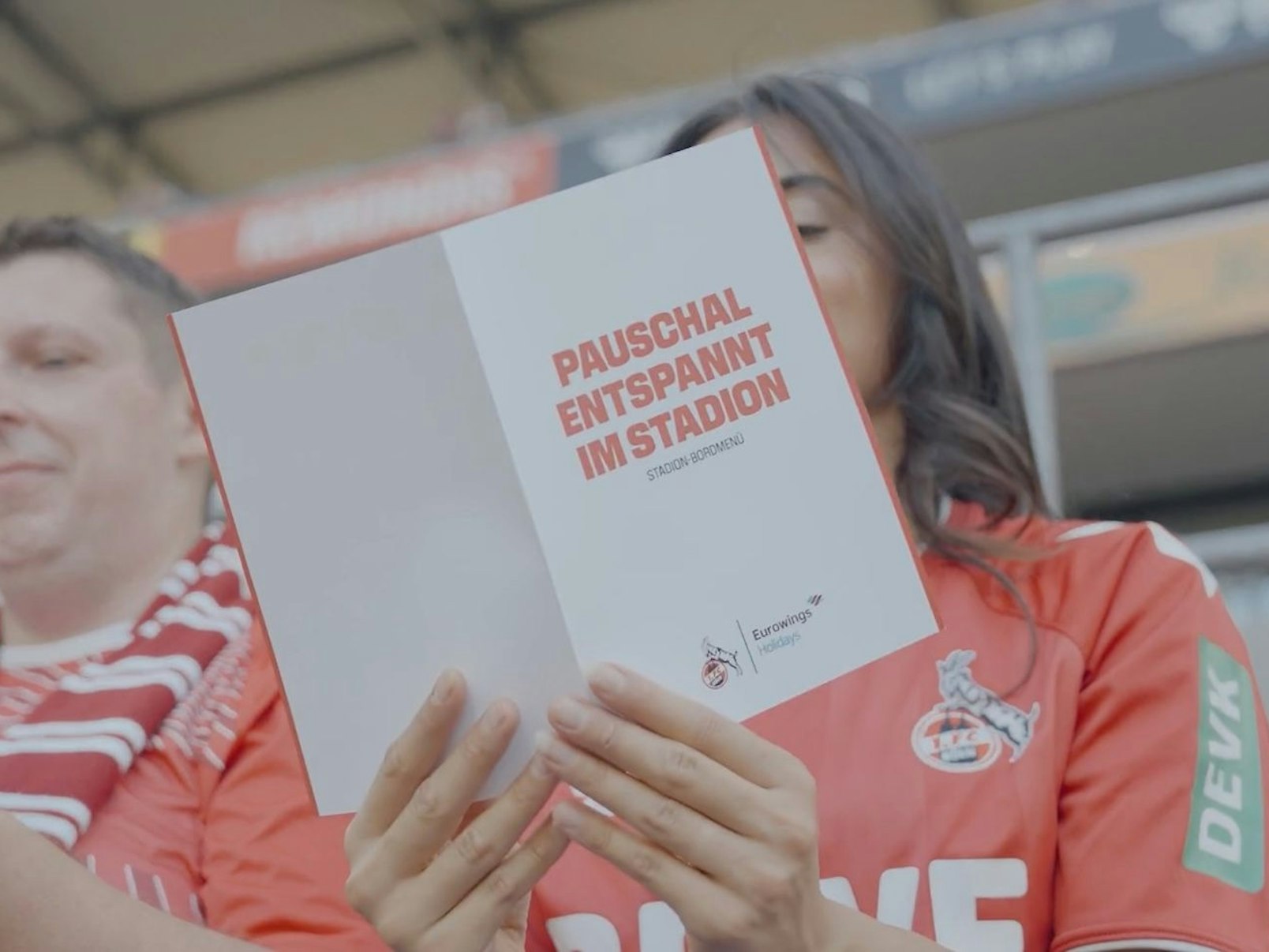 Eine Frau liest im Stadion die Menü-Karte von Eurowings Holidays.